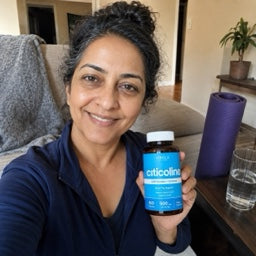Woman holding an Orela Citicoline bottle at home
